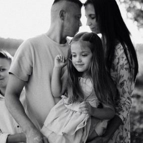 A serene black and white portrait of a family standing by a lake.