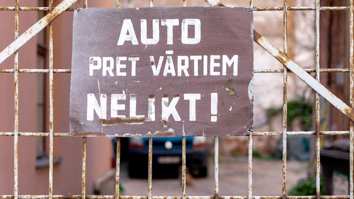 a sign on a gate that says auto pret vartiem nelkt
